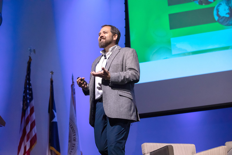 Bearded man in suit standing on stage