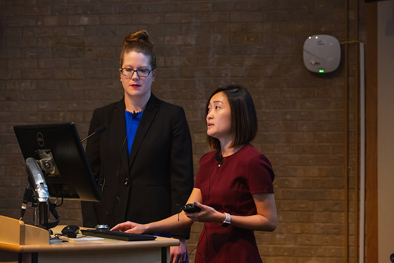 Two women standing at podium speaking