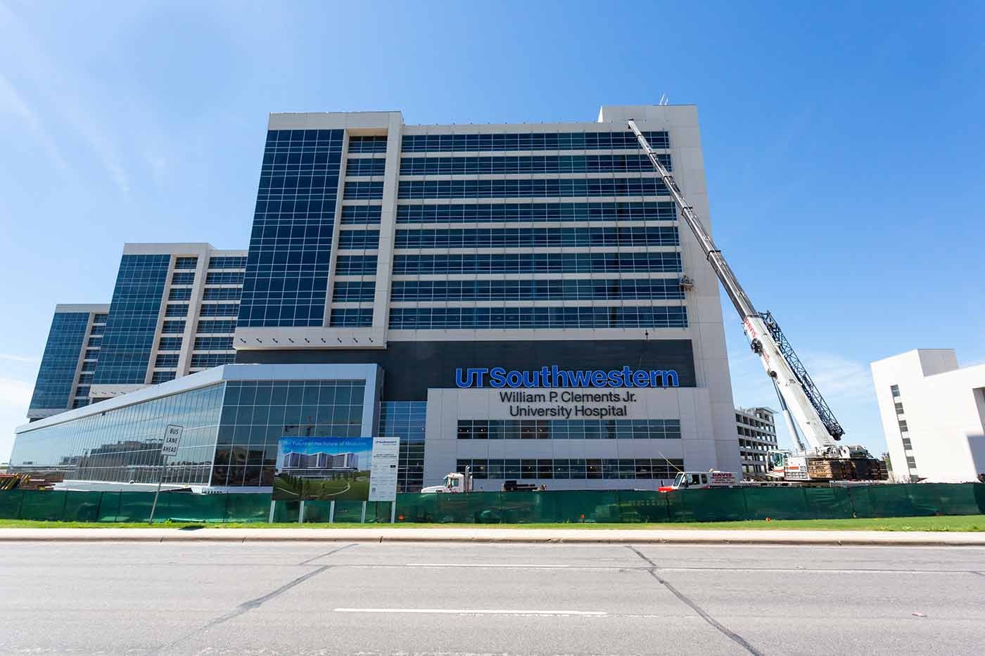 Large glass building with cranes installing sign