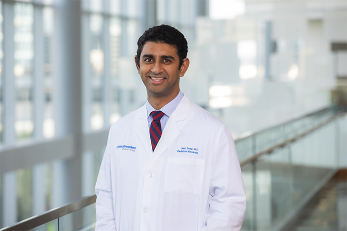 Man with trim beard, red tie, and labcoat on