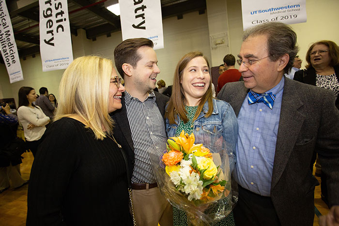 four people smiling with flowers