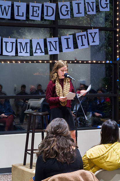 Woman standing in front of audience reading into a microphone