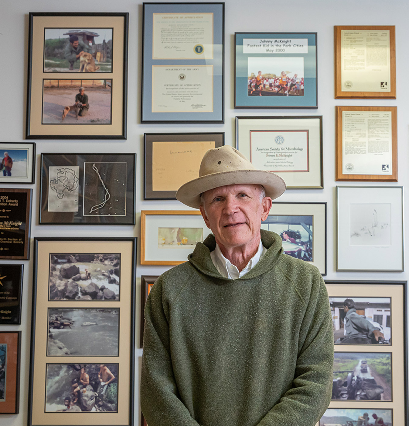 Man in hat sitting in front of photos