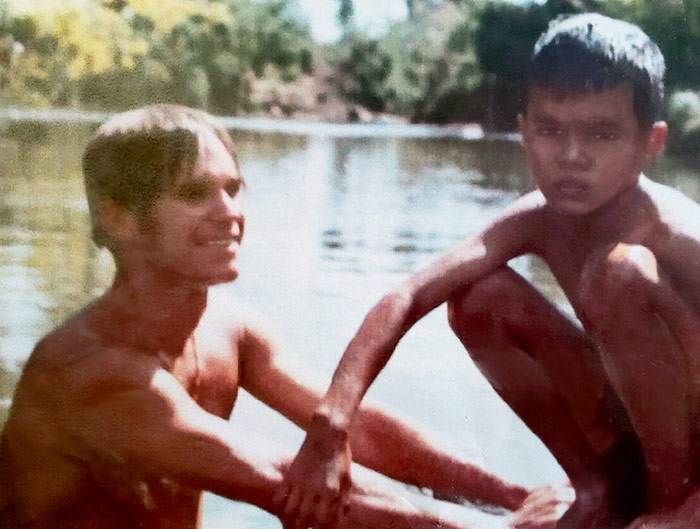 Man in water next to boy sitting on dock