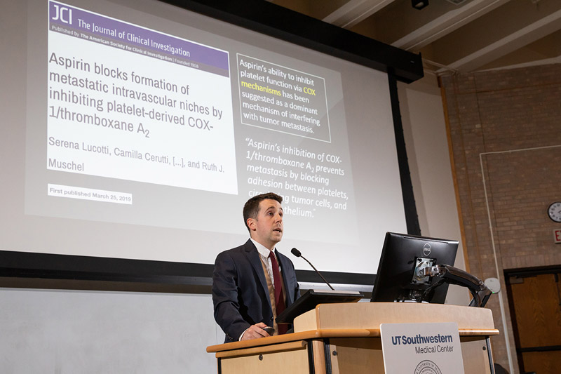 Man in suit standing at podium in front of a screen