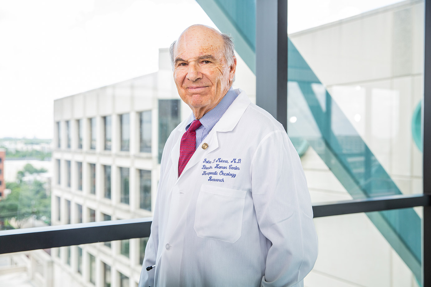 Man with gray hair, red tie, wearing white lab coat