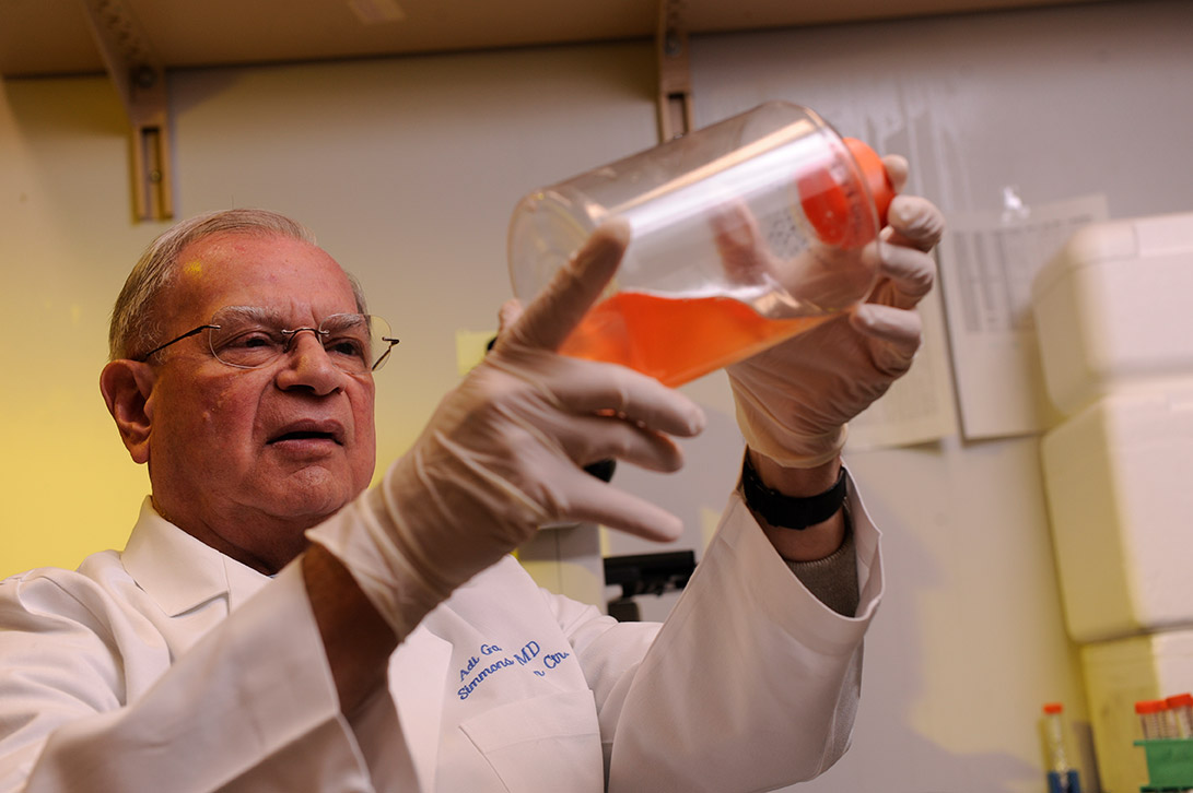 Man in lab coat, wearing gloves, looking at bottle