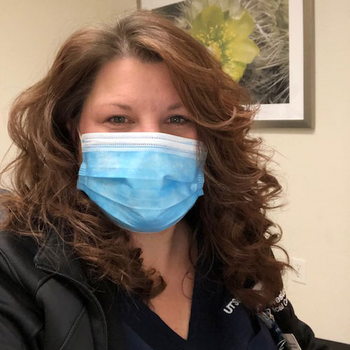 Woman with brown hair, wearing paper mask