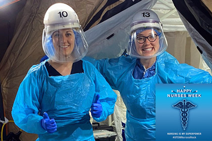 Two nurses in gowns and face shields smiling