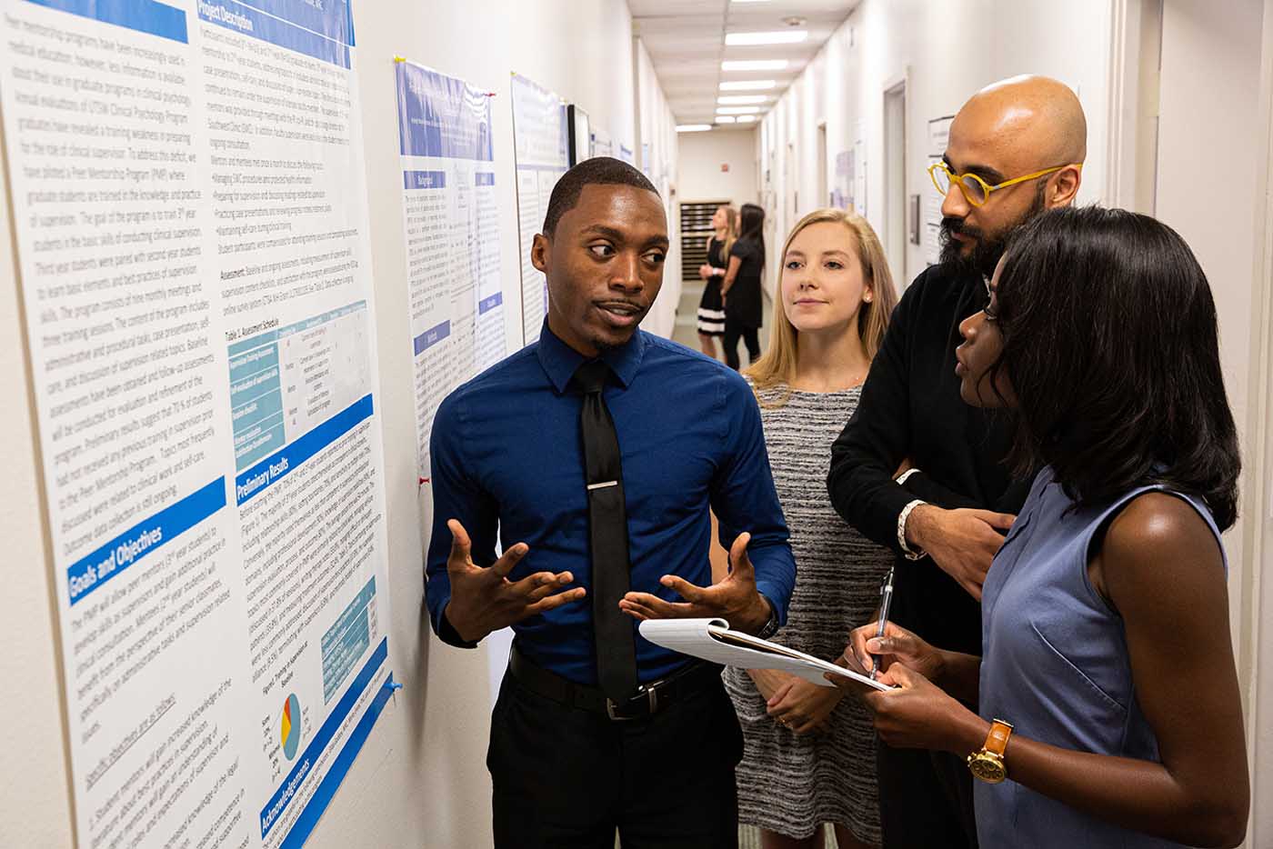 Four people in hallway looking at postser on wall