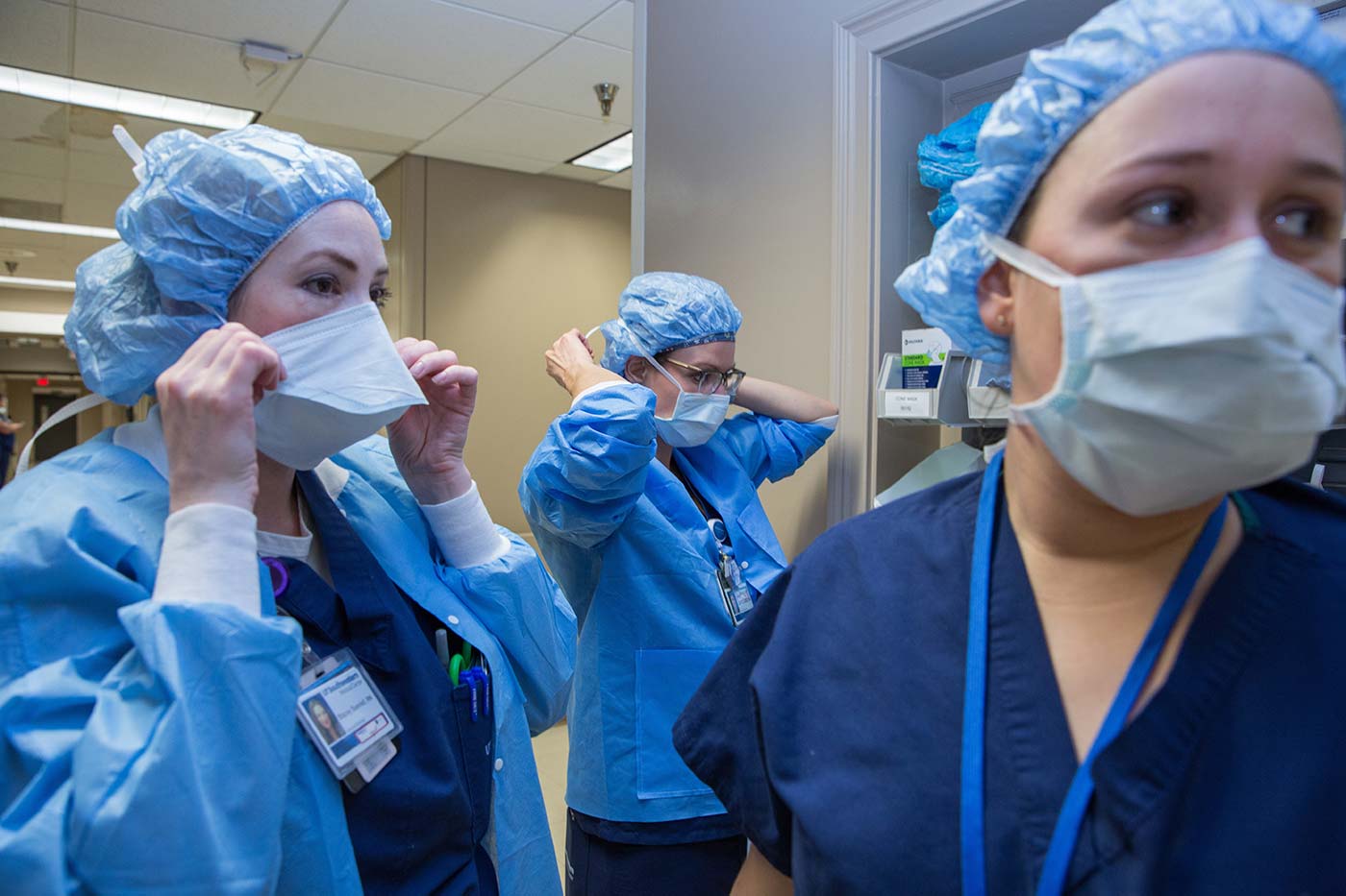 Thre people in medical gowns donning masks