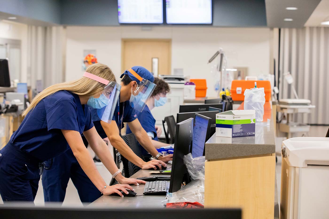 Medical personnel in scrubs and masks at computers