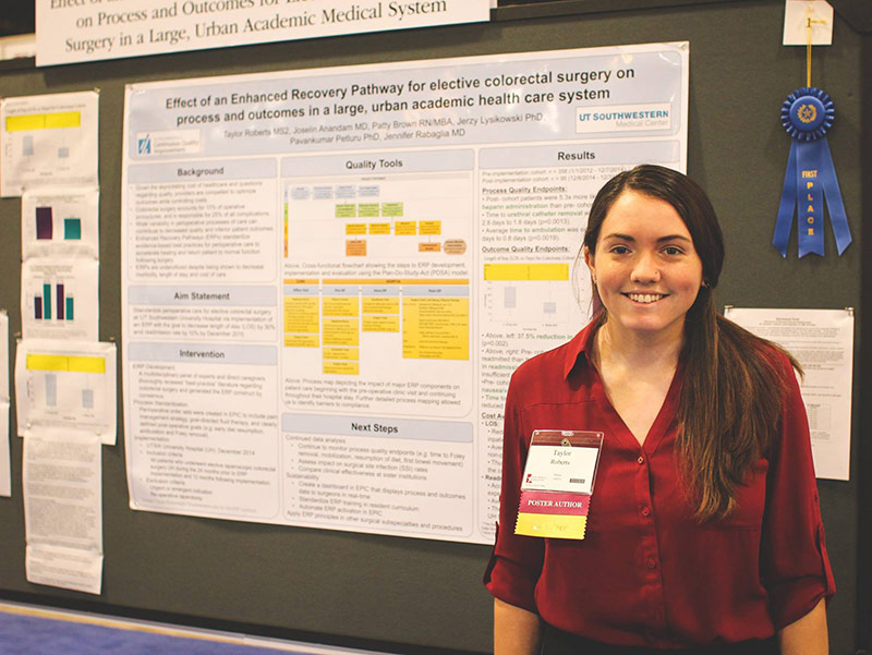 Woman in red shirt standing by research poster