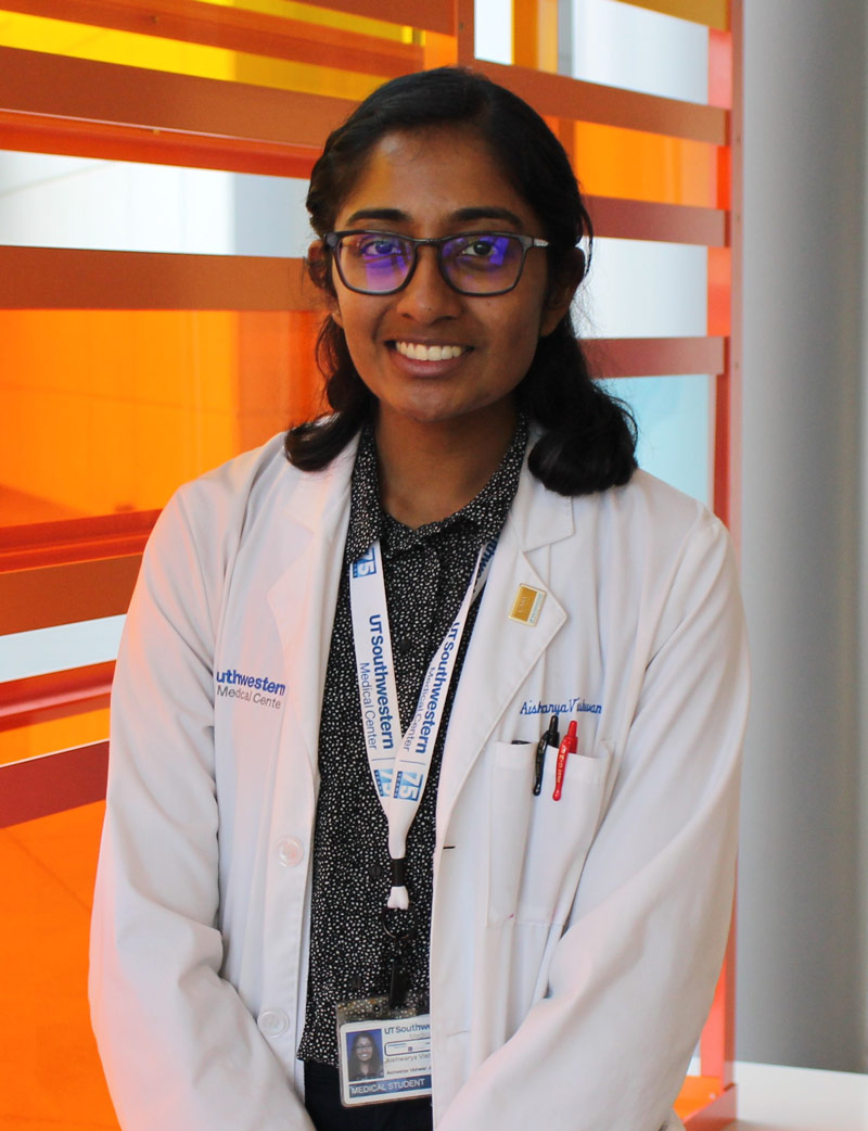 Woman wearing glasses and black shirt wearing white lab coat