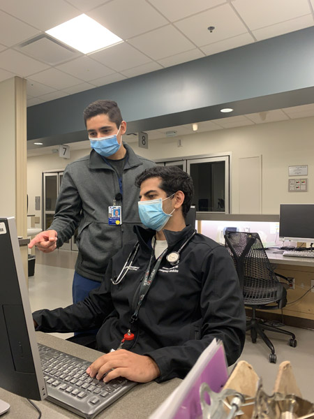 Two men in masks looking at a computer