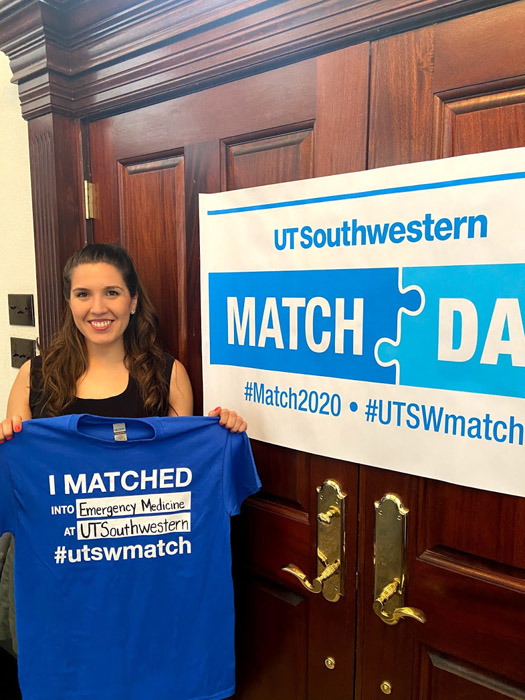 Woman holding shirt with match day information on it