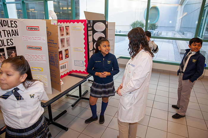 Girl talking to woman in white lab coat about her poster