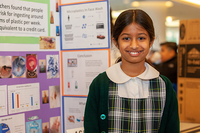 Girl smiling in front of posterboard