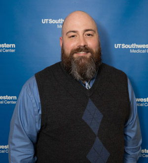 Man with beard wearing blue dress shirt, tie, sweater vest