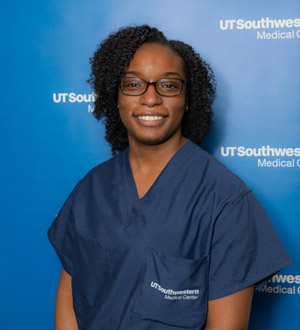 Woman with glasses, black hair, wearing scrubs