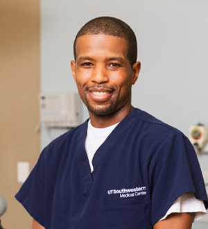 Man with shaved head wearing scrubs