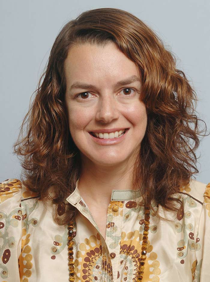 Woman with golden brown hair, wearign sun colored shirt and necklace