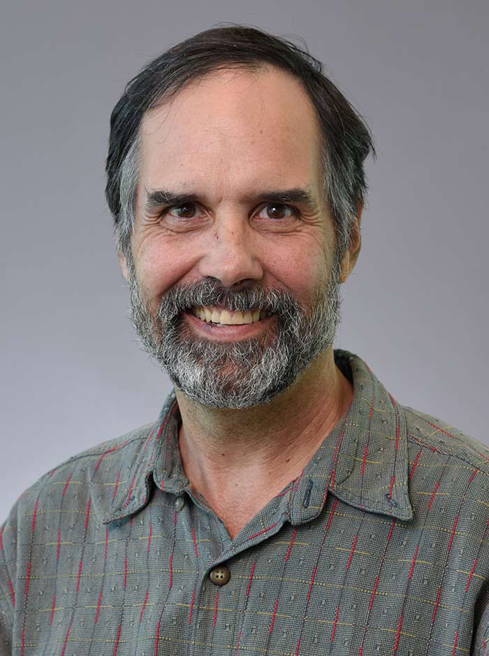 Man with graying beard, wearing green button down shirt