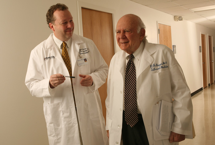 Two men in lab coats walking in a hallway