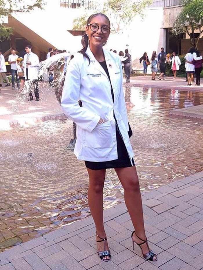 Woman in white lab coat standing in front of fountain