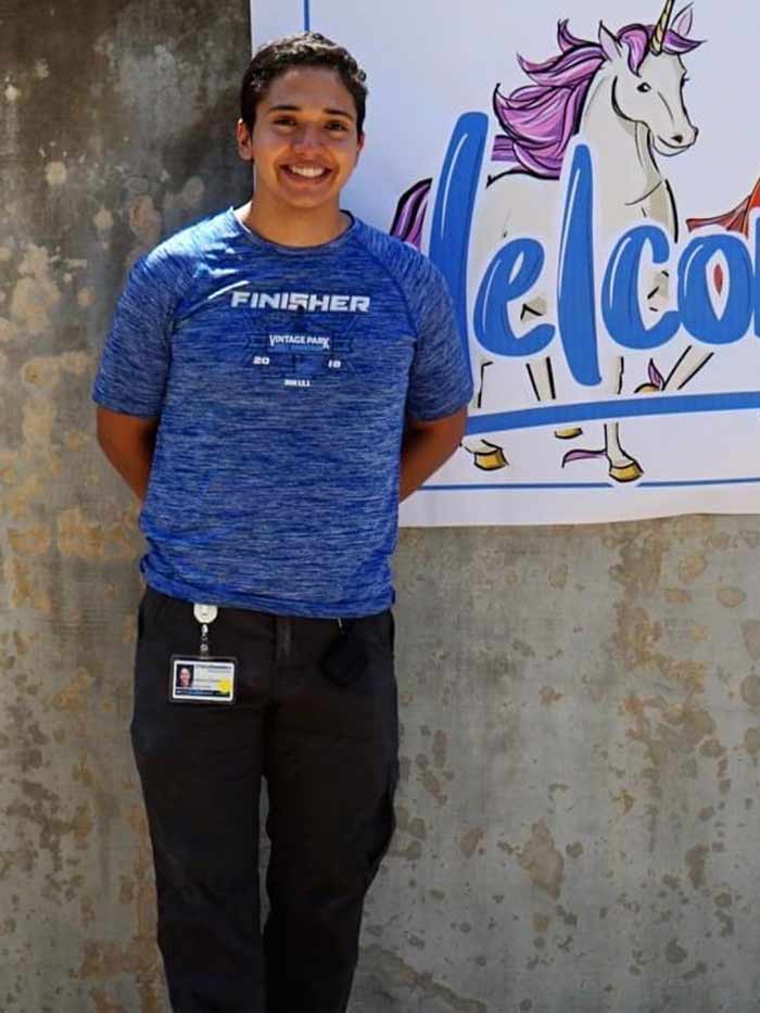 Man in blue shirt standing in front of welcome sign