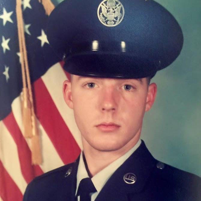 Man in dress uniform in front of flag