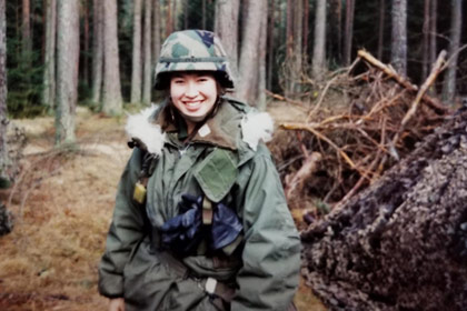 Woman in helmet and military fatigues in a forest