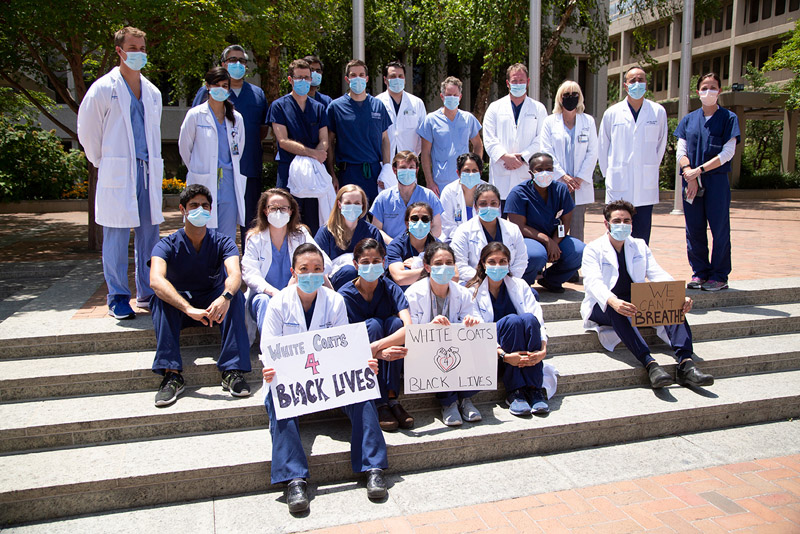People in scrubs, white lab coats, wearing surgical masks, holding signs in support of black lives