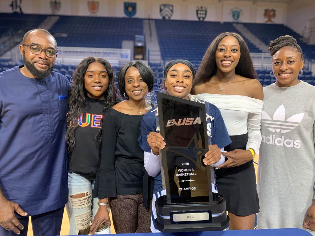 Group of six people on basketball court, holding trophy and smiling