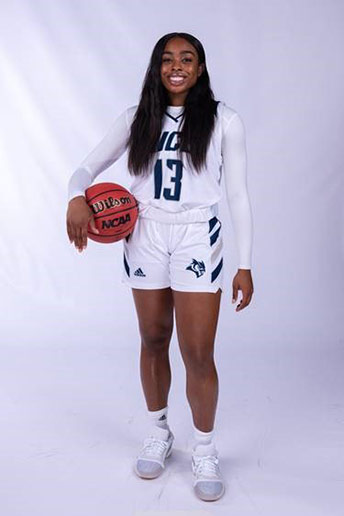 Woman in basketball uniform, holding basketball