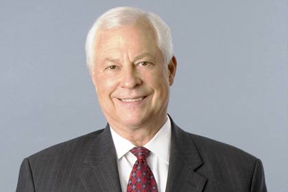 Man in gray suit with white hair smiling