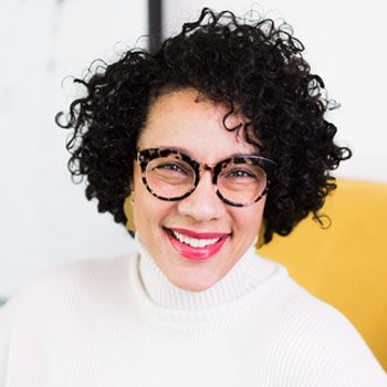 Woman with dark hair and glasses, white sweater