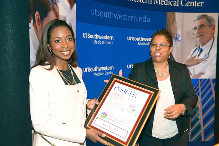 Two women, one holding an INSIGHT framed award