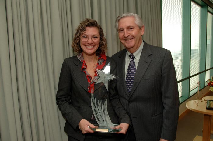 Woman holding award next to man