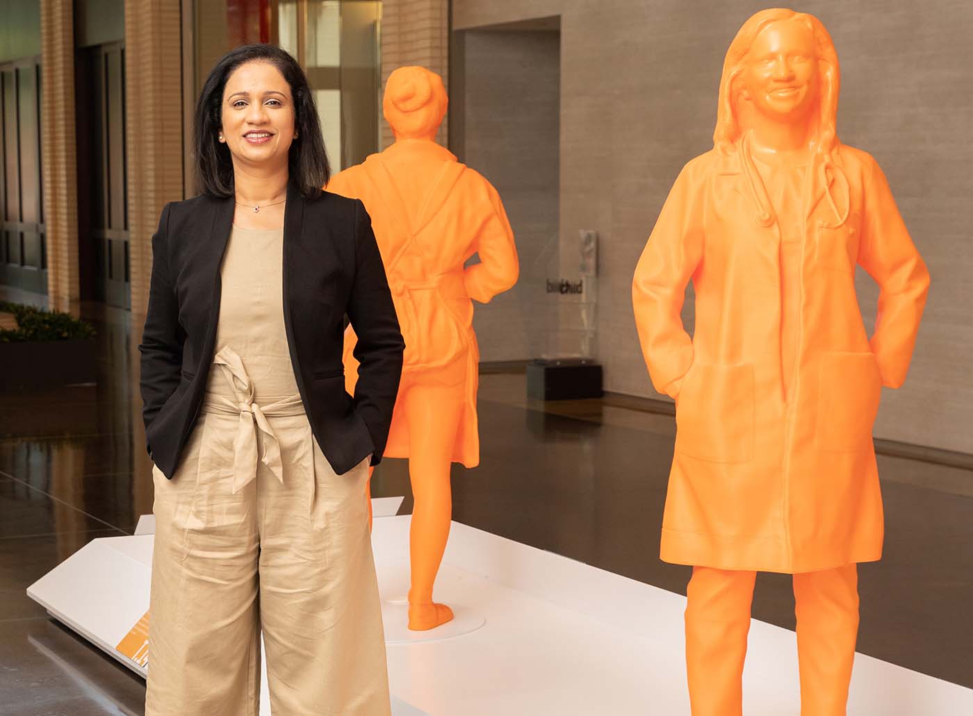 Woman in black jacket standing next to statue of her