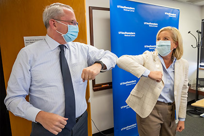 Man and woman in masks bumping elbows