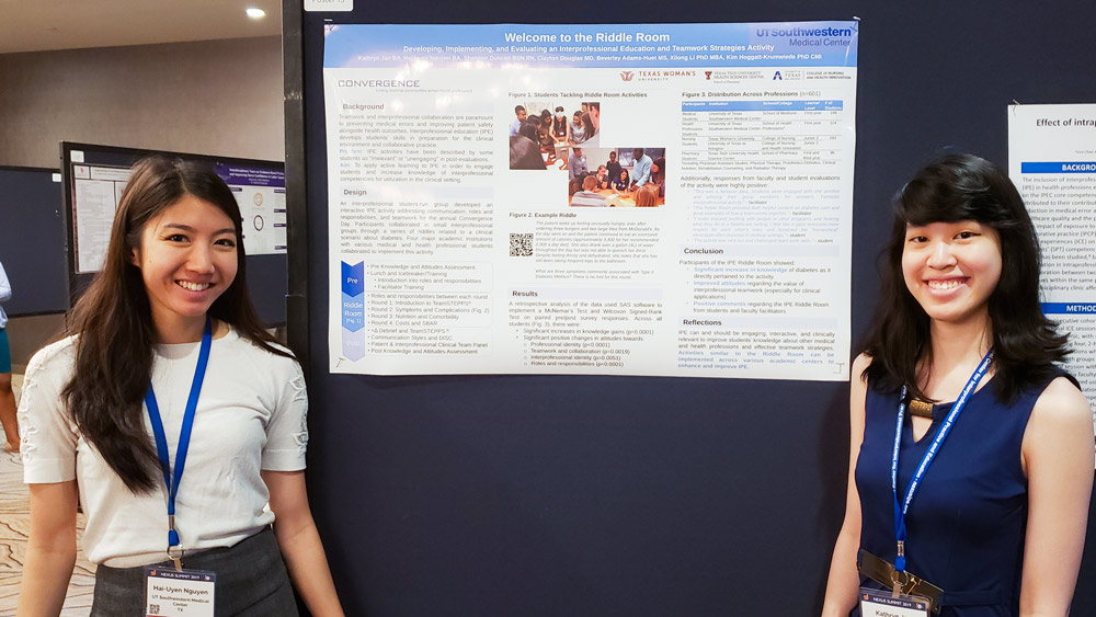 Two women smiling standing next to poster board