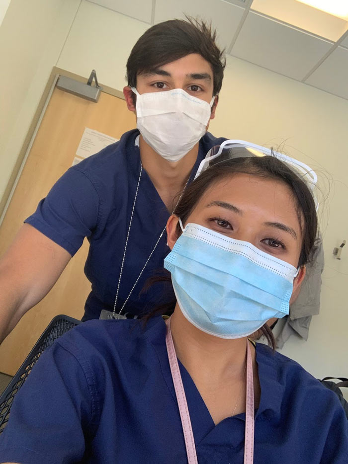 Two people in scrubs and masks taking selfie together