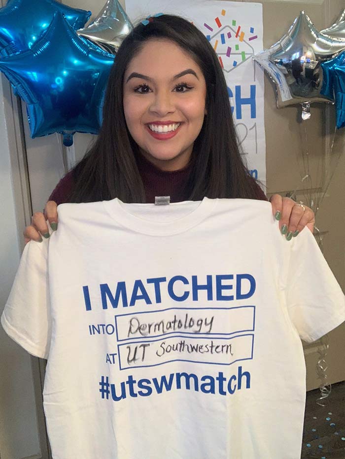 Woman holding shirt that says I matched into dermatology