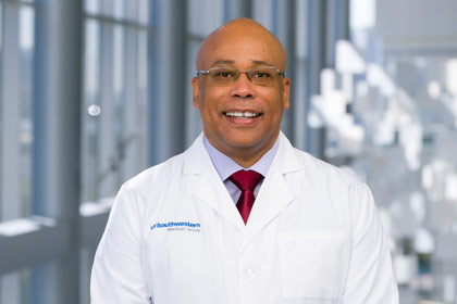 Man with shaved head in white coat