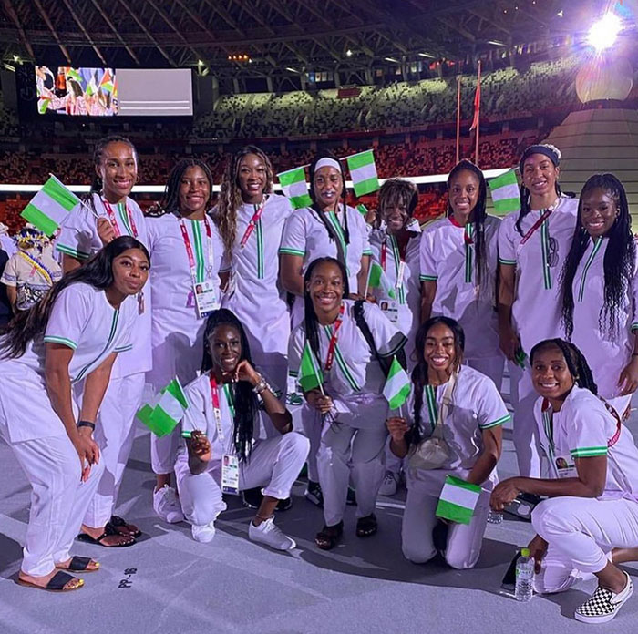 Group of women in white uniforms in a stadium waving Nigerian flags