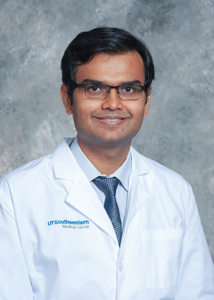 Man with dark hair and glasses and a white coat