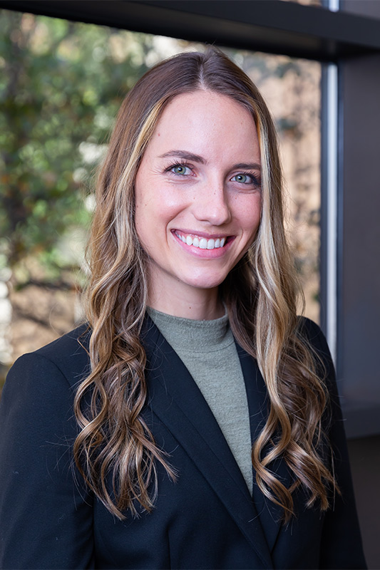 Woman with long brown hair and dark suit jacket