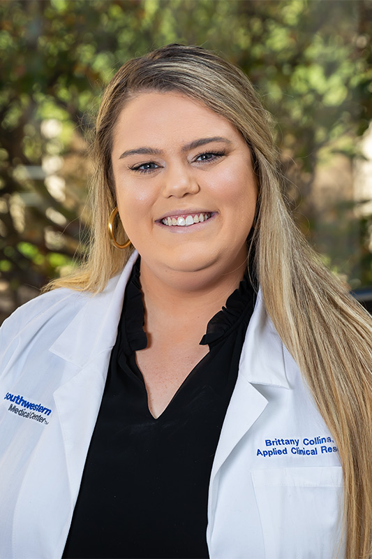 Woman in white lab coat over black shirt with long blond hair