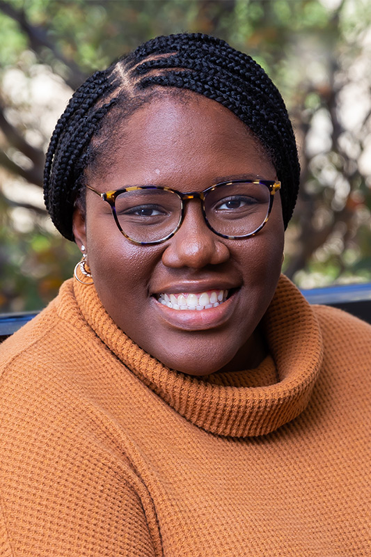 Woman with black braids, rust sweater